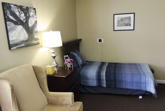 A cozy bedroom with a single bed, nightstand, and lamp.