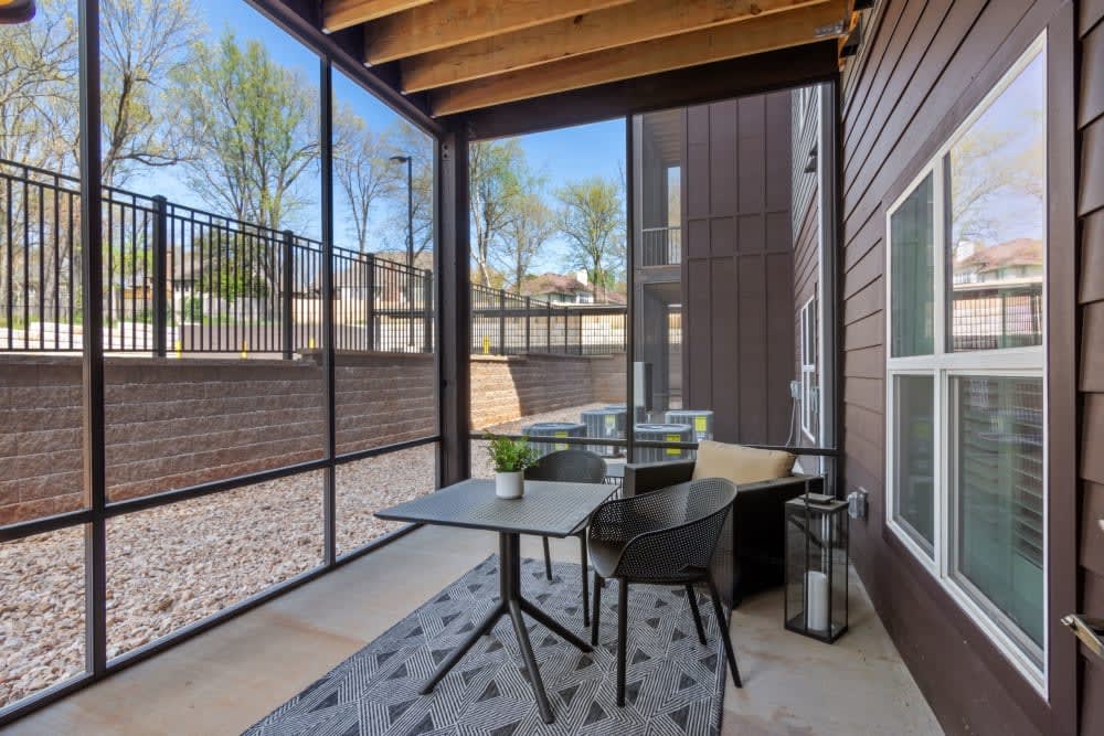 A cozy screened patio with a table, chairs, and potted plants.