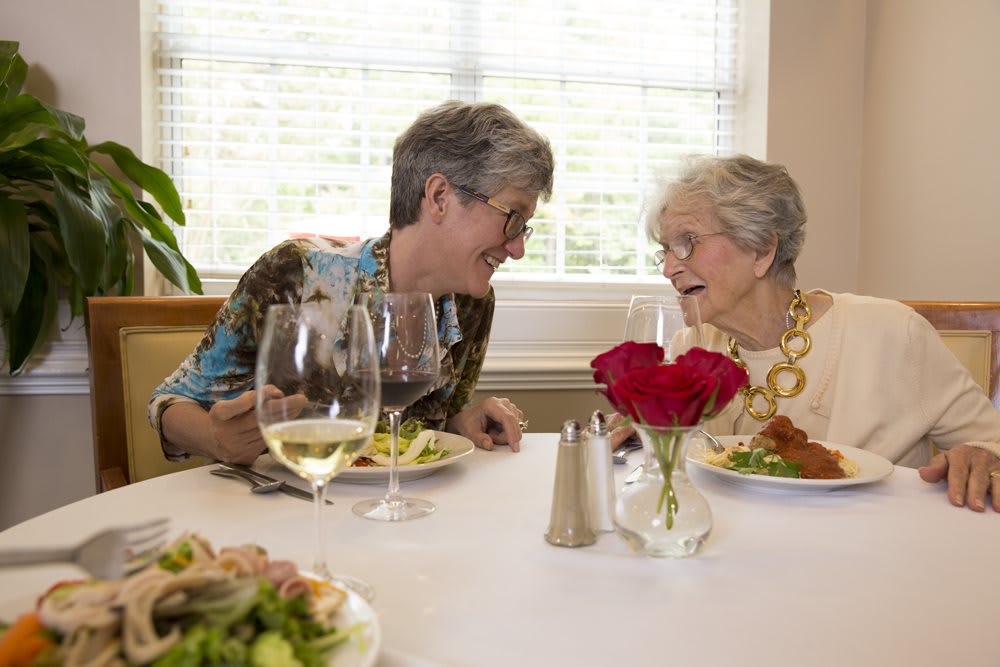 Two elderly women enjoying a meal and conversation together.
