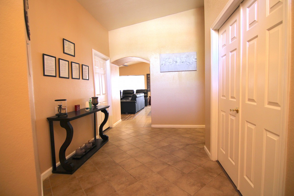 A well-lit hallway with stylish furniture and decor leading to another room.