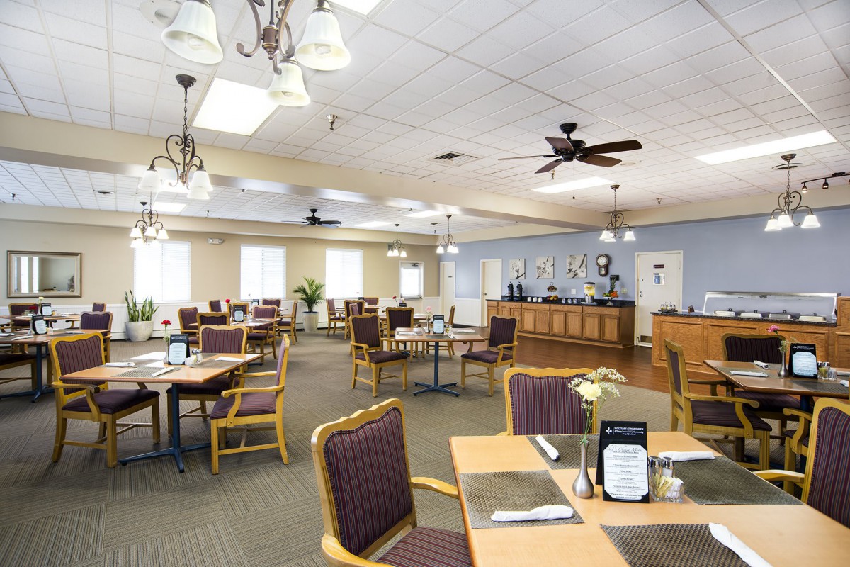 Spacious dining area with tables and chairs, featuring ceiling fans and ambient lighting.