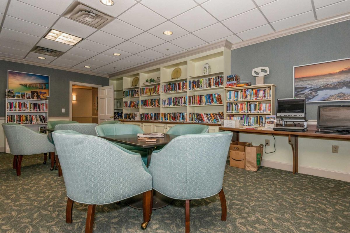 A cozy library room with a central meeting table and surrounding bookshelves.
