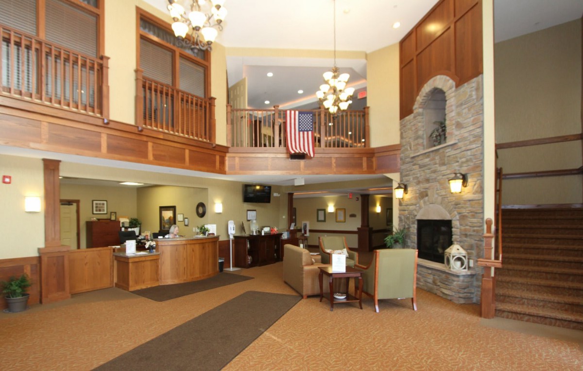 A spacious lobby with a reception desk, seating area, chandeliers, and a fireplace.