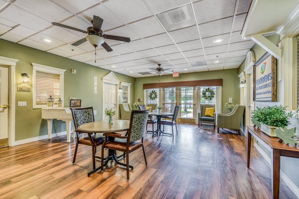 A cozy dining area with tables, chairs, and ceiling fans, featuring green walls and wood flooring.