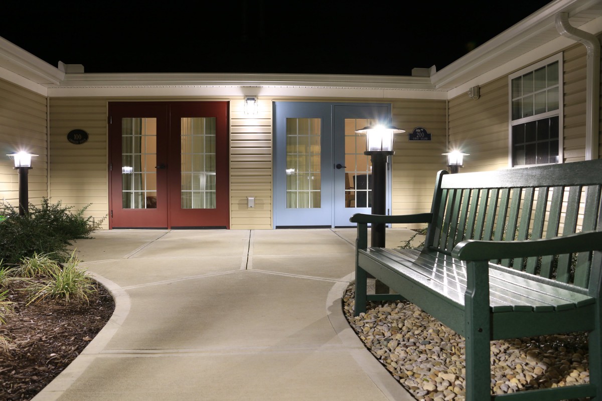 A well-lit outdoor area with a bench and colorful doors at night.
