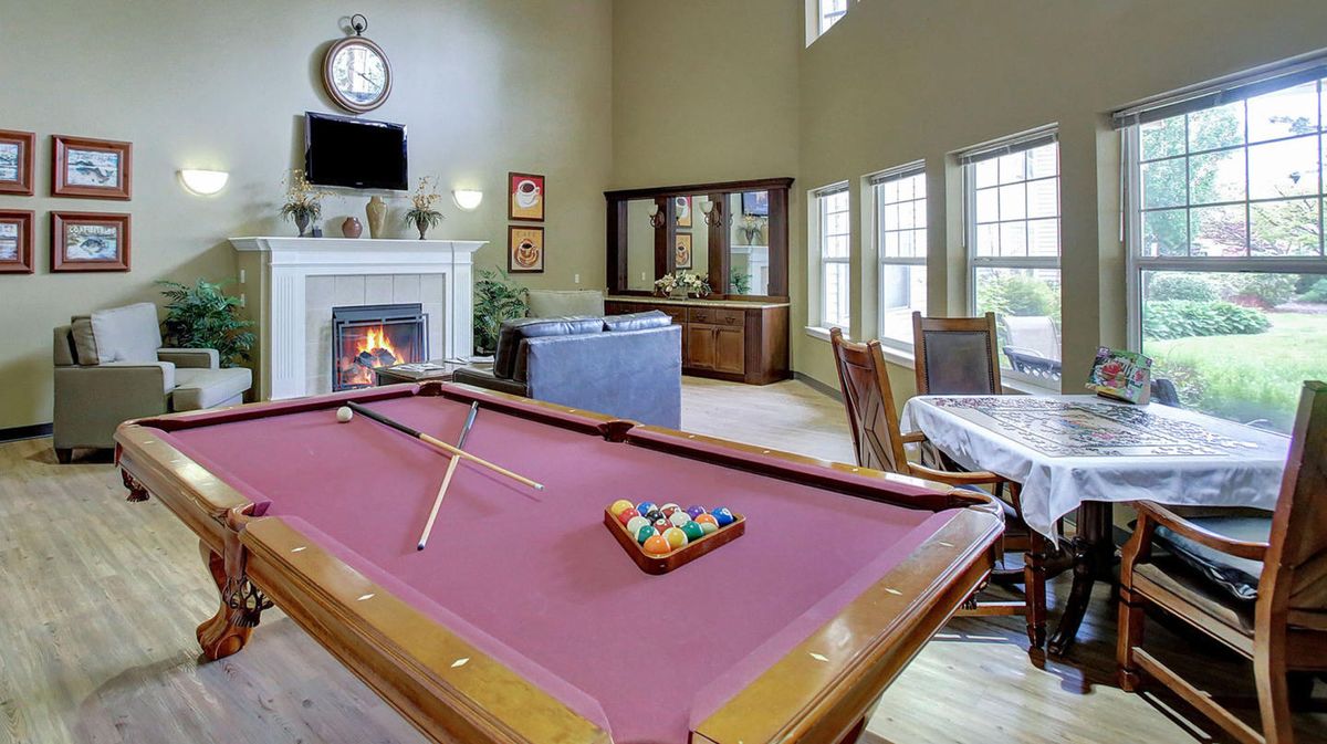 A cozy game room featuring a pool table and a fireplace.