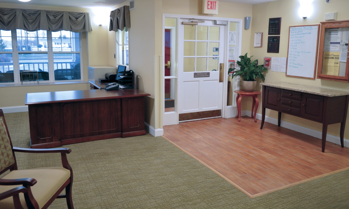 A welcoming lobby area with a desk, plant, and entrance door.