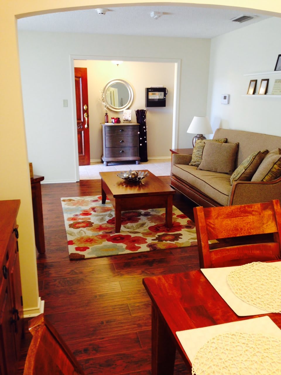 A cozy living room with a sofa, coffee table, and decorative rug on a wooden floor.