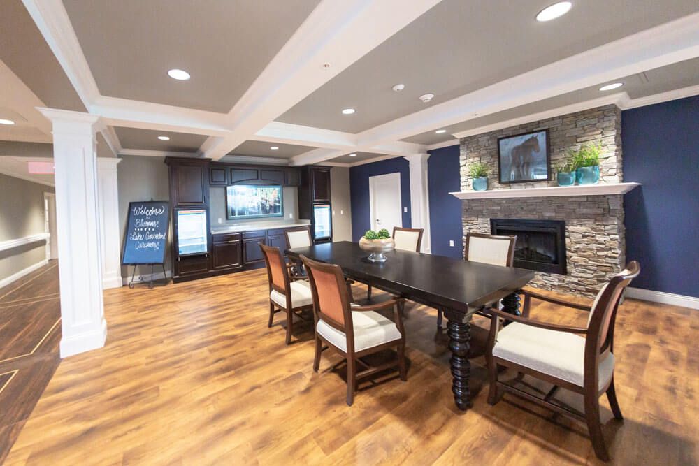 A modern dining room with a large table, surrounded by chairs, featuring hardwood flooring and a fireplace.