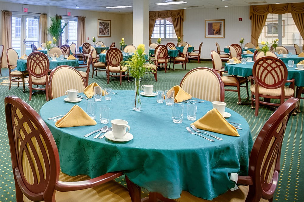 A well-arranged dining area with teal tablecloths, neatly folded napkins, and elegant chairs.
