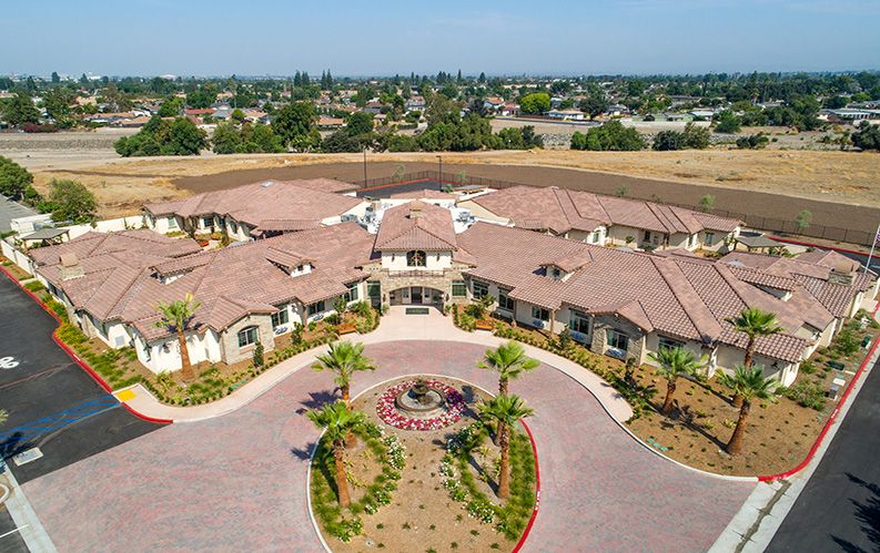Aerial view of a large residential building with landscaped surroundings in a suburban setting.
