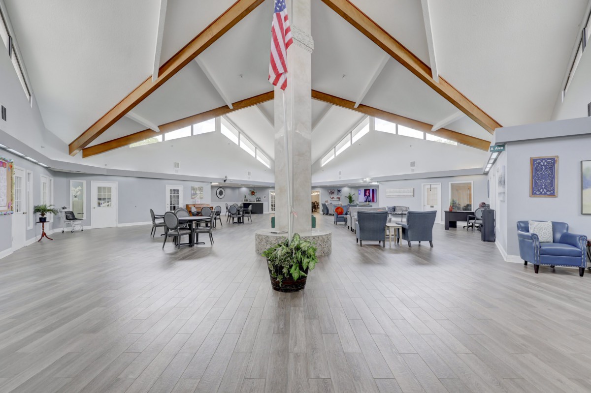 A spacious interior with modern design featuring wooden beams, a central pillar with a potted plant, and an American flag hanging from the ceiling.
