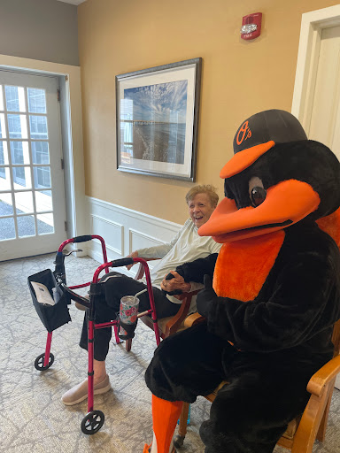 A lively interaction between a mascot and an elderly individual in a community setting.