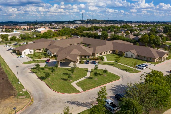 Aerial view of a suburban building with surrounding roads and parked cars.