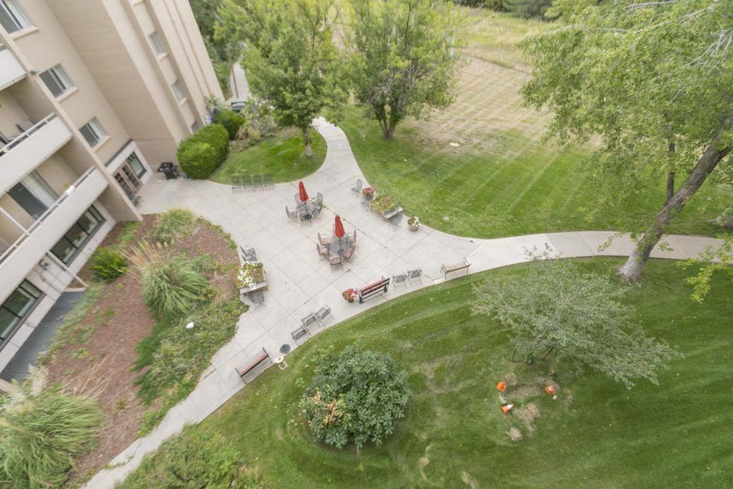Aerial view of a garden area with outdoor seating, surrounded by lush greenery and pathways.