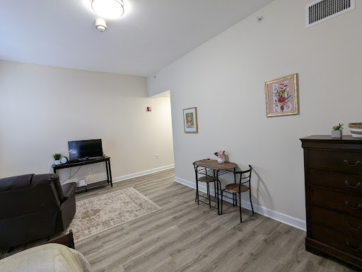 A cozy living room featuring a television, a small table, and decorative artwork.
