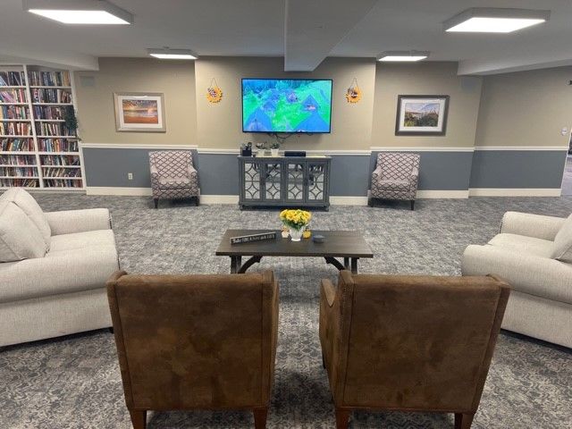 A cozy living room with a seating area and a wall-mounted television.