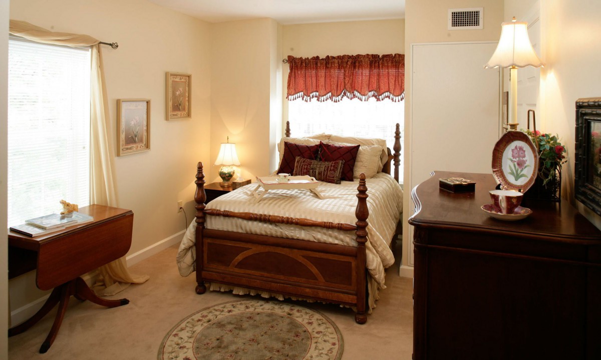 A cozy bedroom with a neatly made bed, a bedside lamp, and decorative elements.