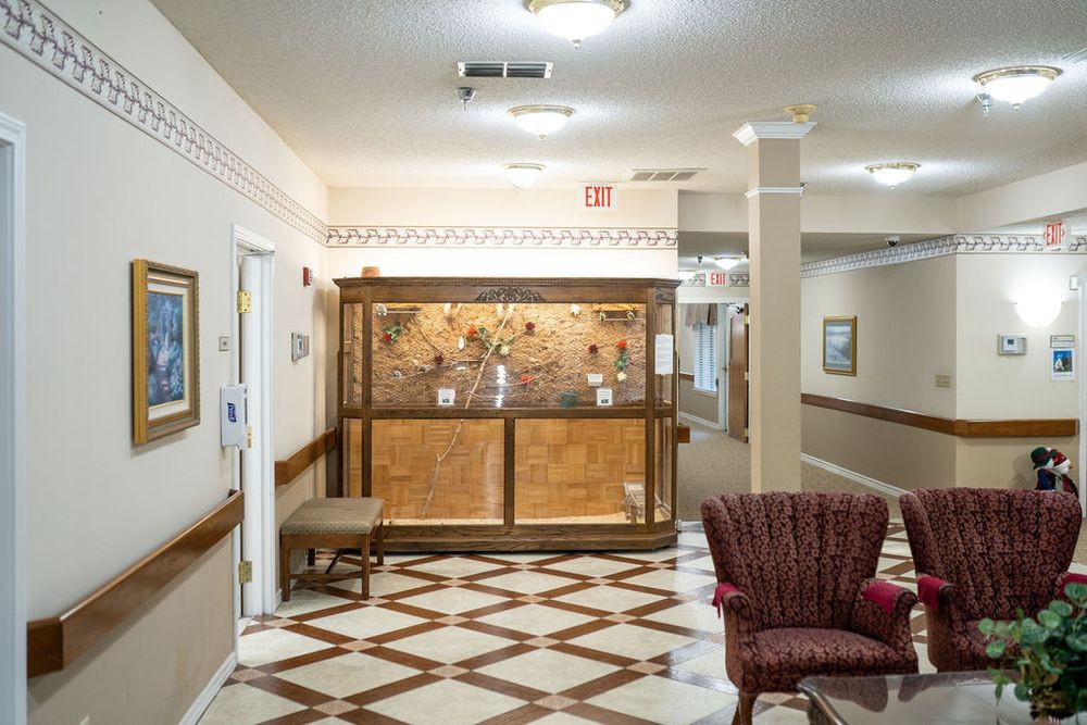A cozy lobby area featuring a decorative display case, patterned flooring, and comfortable seating.
