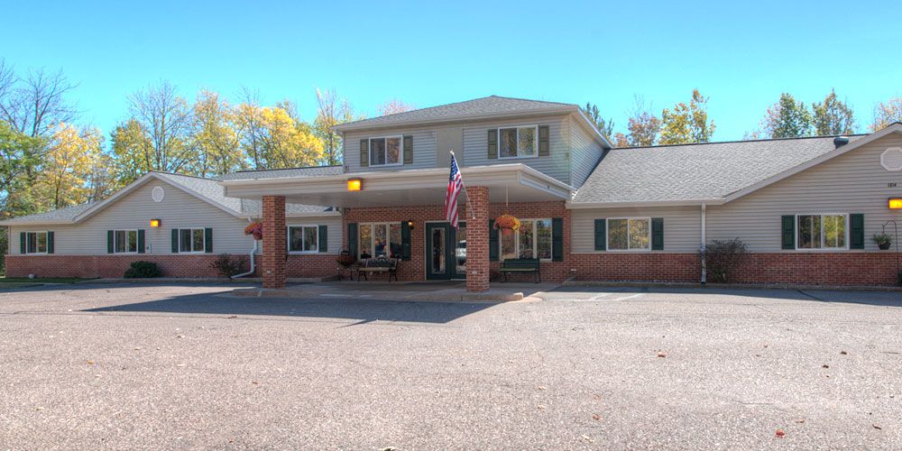A building with an American flag at the entrance and a parking lot in front.