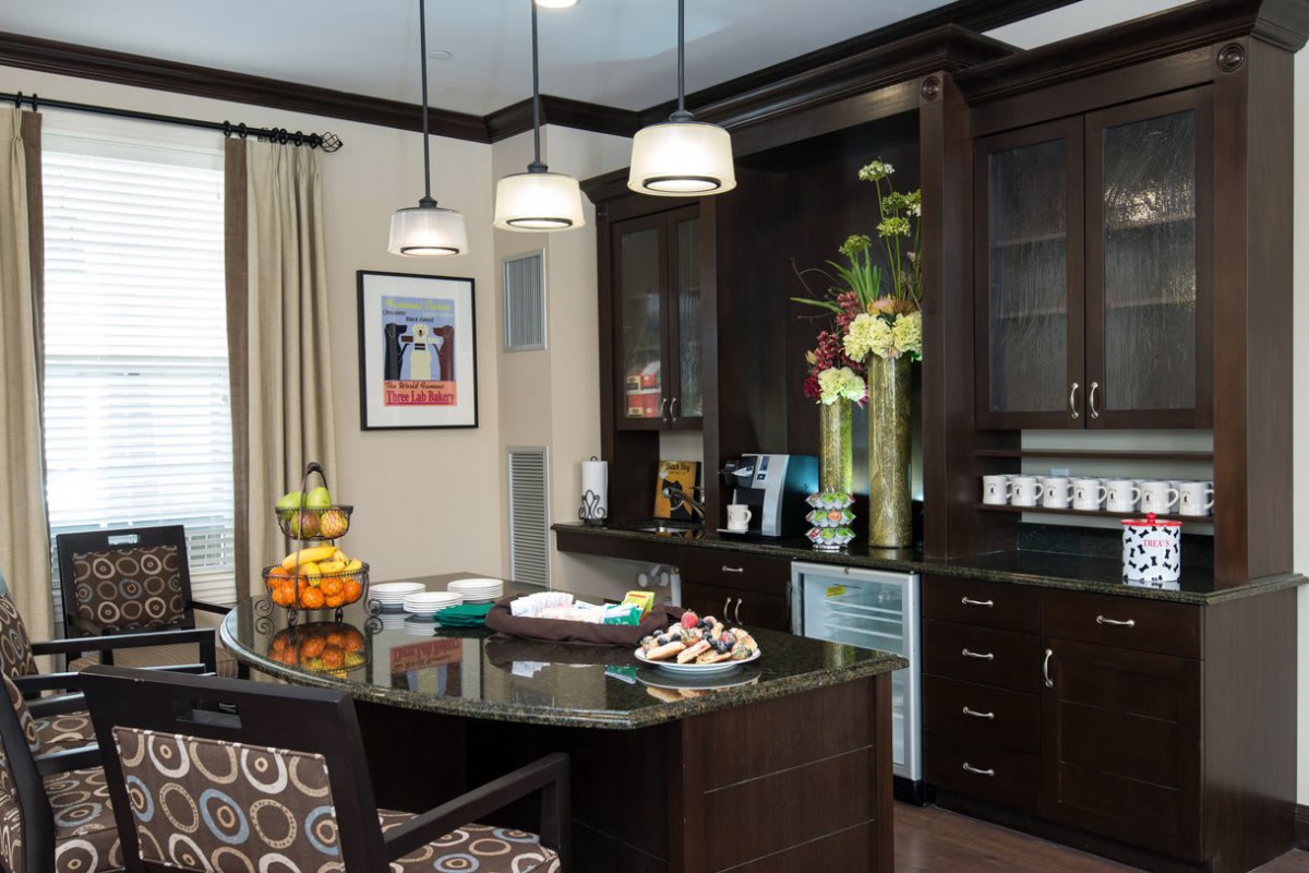 A modern kitchen with dark cabinets, an island counter, and stylish hanging lights.