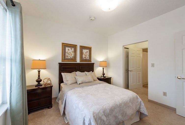 A cozy bedroom with a neatly made bed, flanked by two lamps on nightstands.