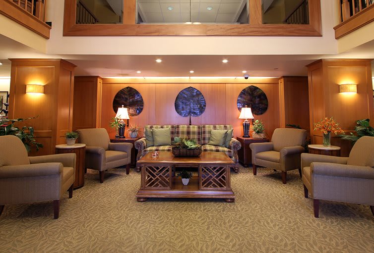 A cozy lobby seating area with comfortable chairs, a sofa, decorative lamps, and a central table.