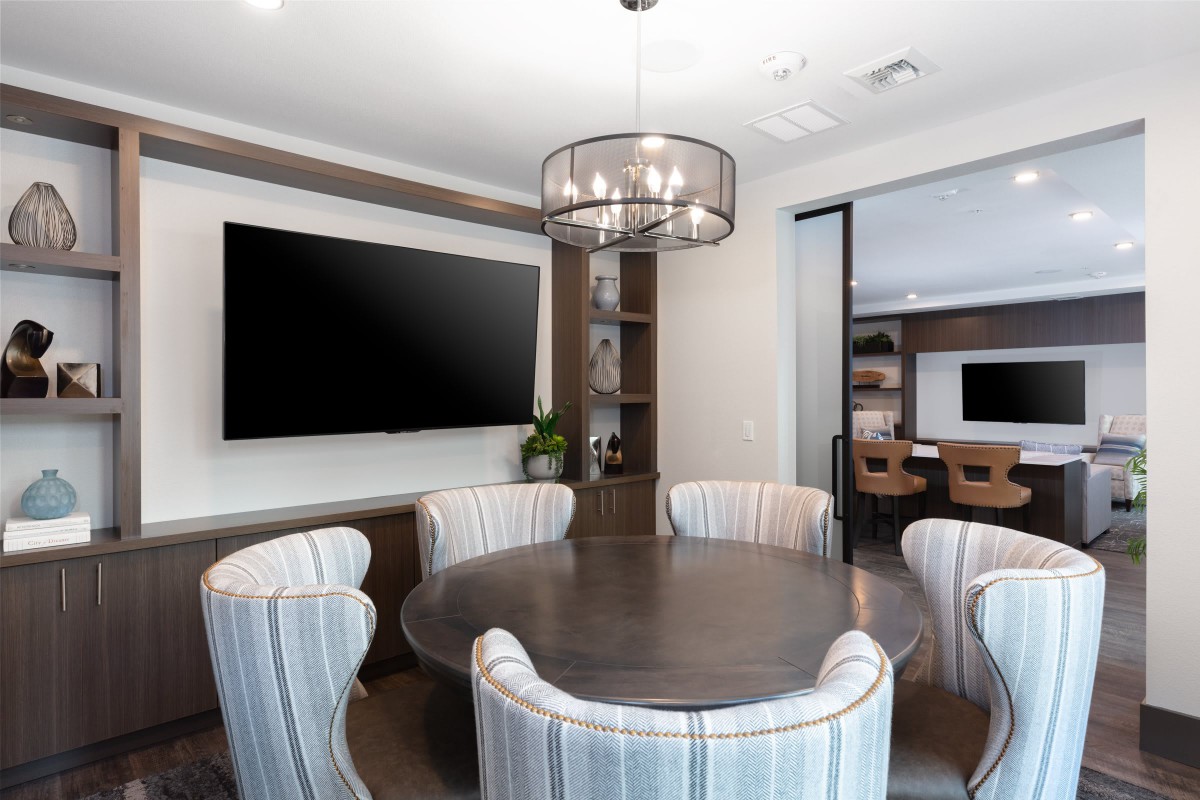 A modern conference room featuring a round table and a large screen, with minimalist decor and interior lighting.