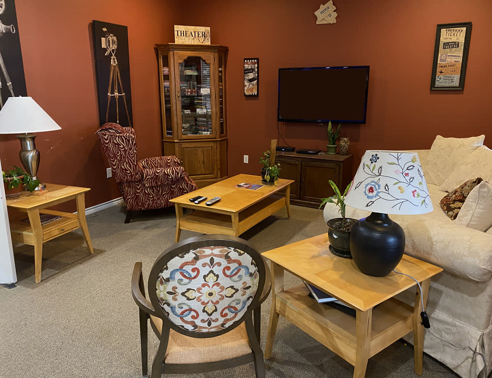 A cozy living room with various furniture pieces, including a coffee table, armchair, cabinet, and a TV.