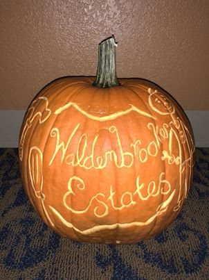 A carved pumpkin displaying the words 'Waldenbrook Estates', illuminated from within.