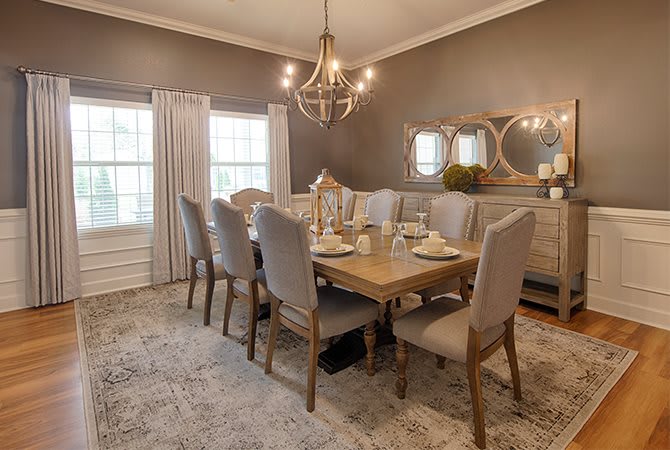 A beautifully decorated dining room with a large wooden table and elegant chairs beneath a chandelier.