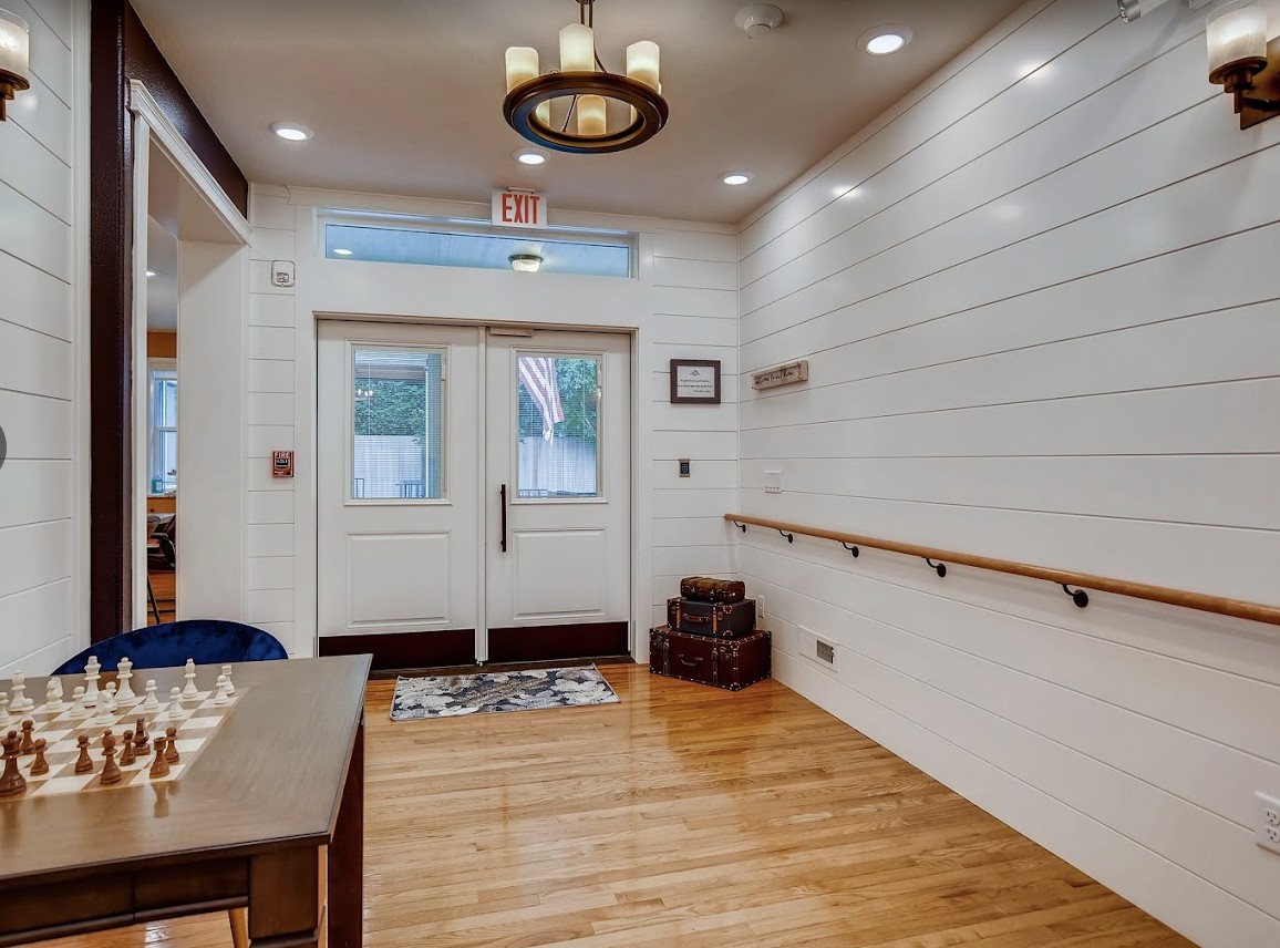 A modern entryway featuring wood flooring, white shiplap walls, and stylish ceiling lighting.