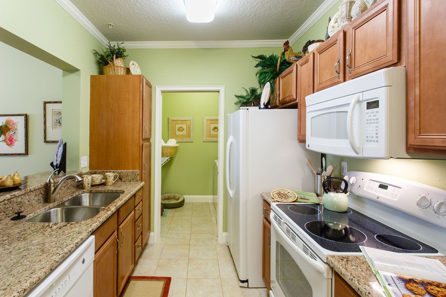 A well-organized kitchen featuring wooden cabinets, modern appliances, and soft green walls.