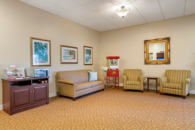 A cozy waiting room with comfortable seating, artwork on the walls, and a popcorn machine.