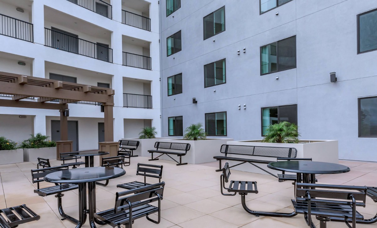 A modern apartment courtyard with outdoor seating and tables.