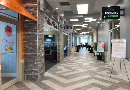 A view of a modern shopping mall corridor featuring various storefronts and contemporary design elements.
