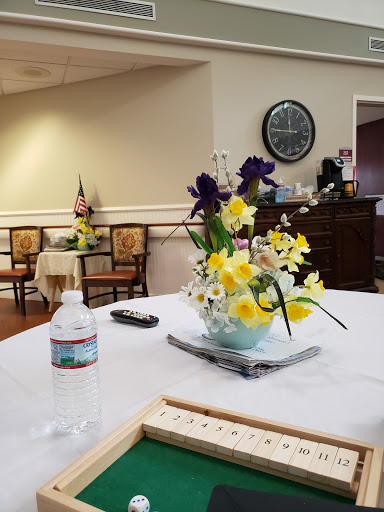 A cozy community room featuring a floral arrangement on the table and comfortable seating.