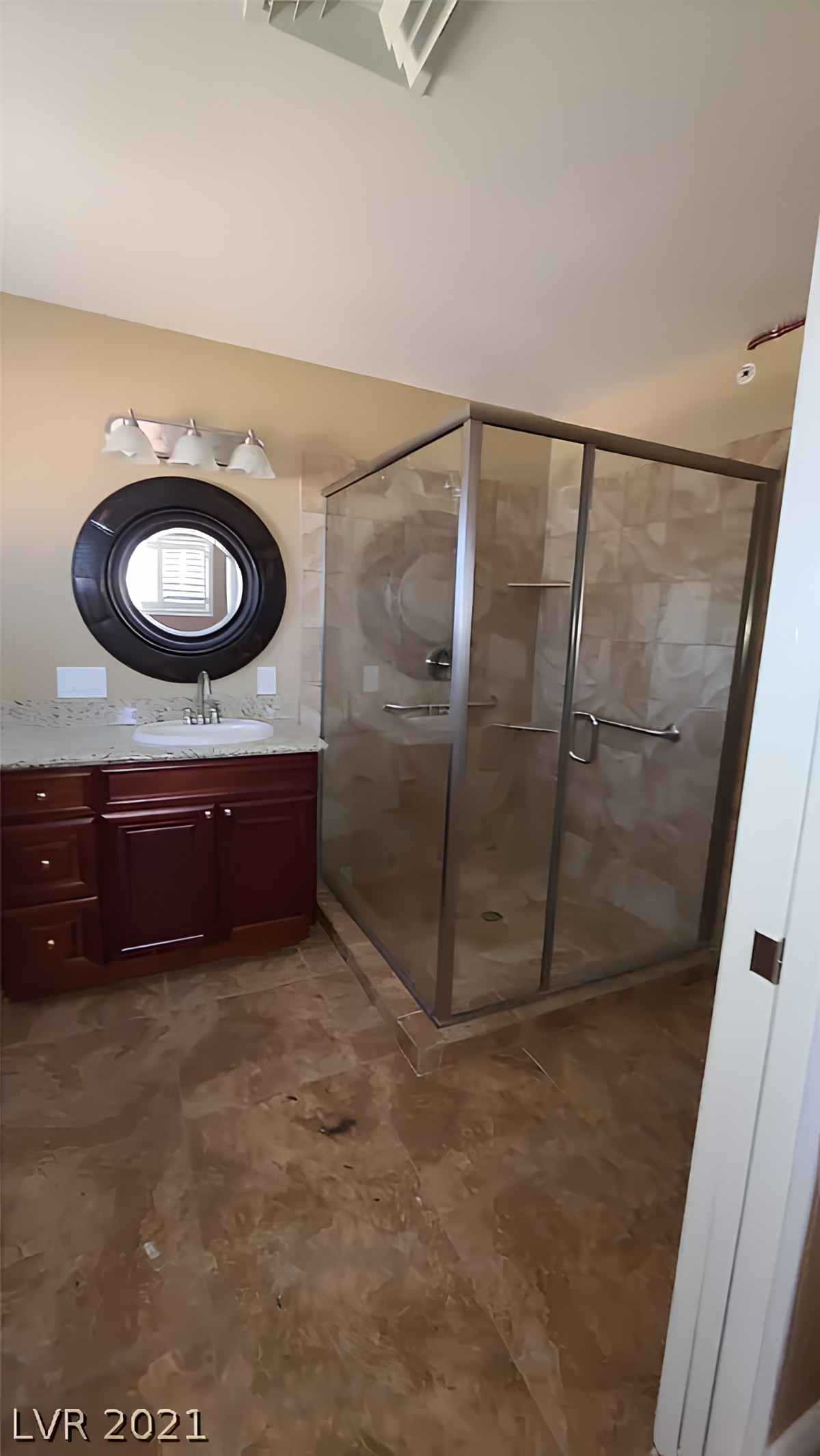 A modern bathroom with a glass-enclosed shower and a wooden vanity.