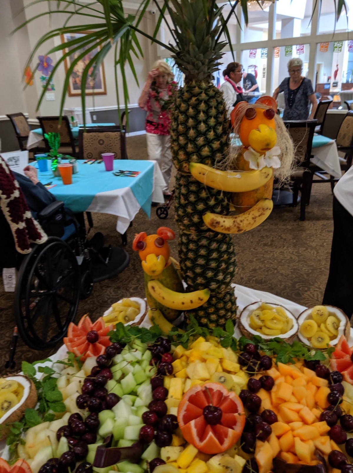 A creative fruit sculpture featuring bananas and pineapples, displayed as part of a buffet table arrangement.