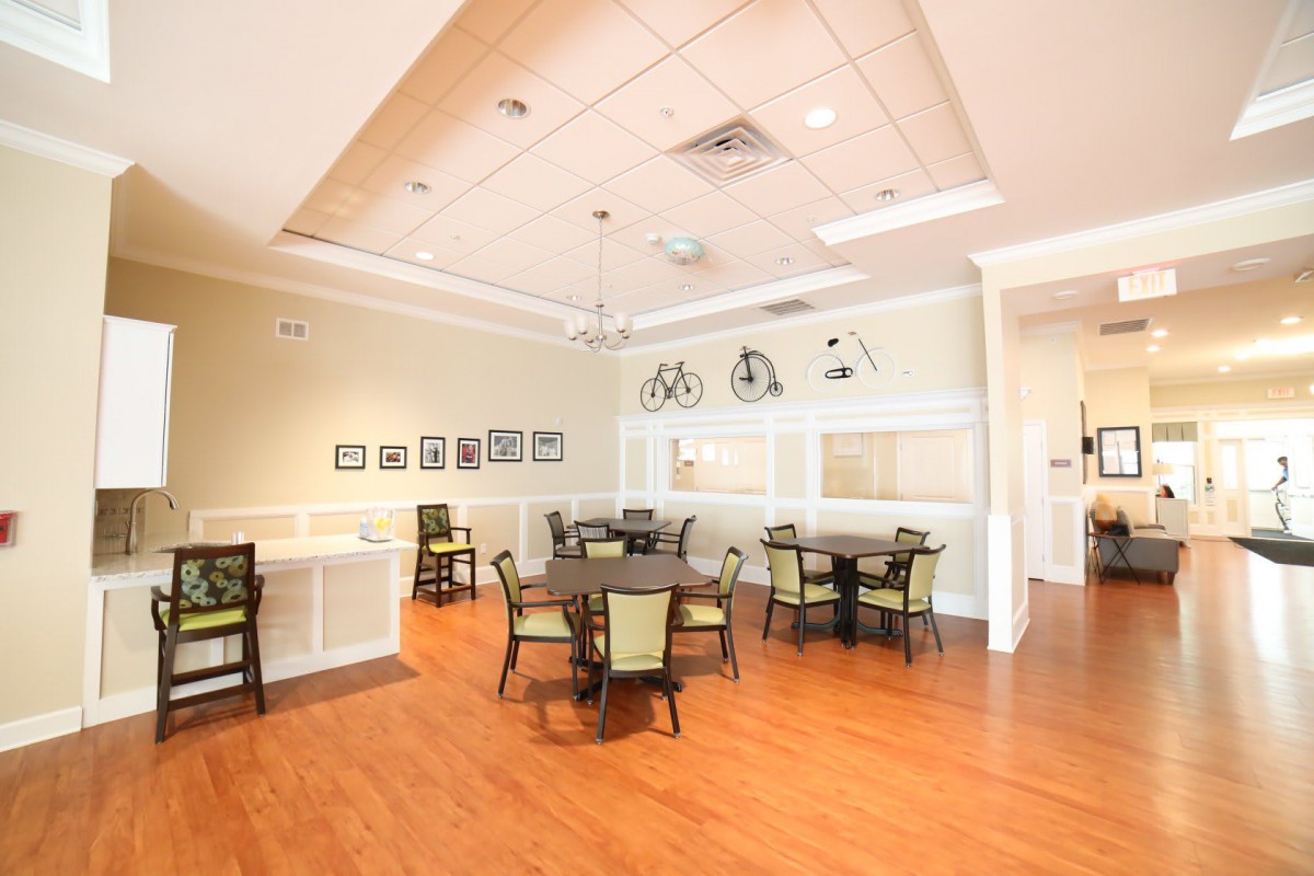 A bright and inviting dining area featuring multiple tables and chairs, warm wooden flooring, and decorative lighting.