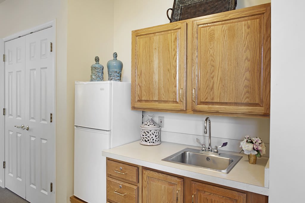 A small kitchen area with wooden cabinets, a white fridge, and decorative items on the countertop.