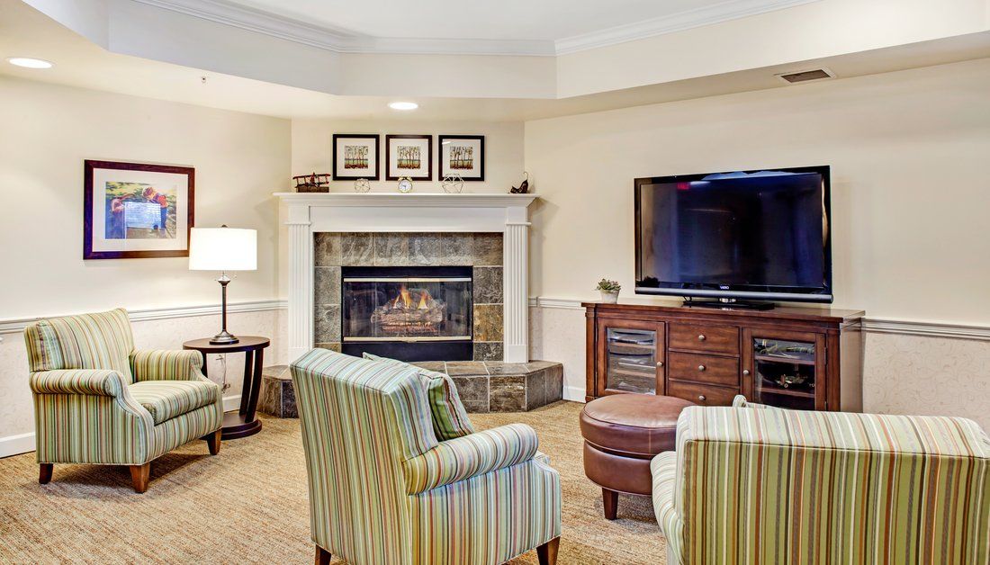 A cozy living room featuring a fireplace, a large television, and comfortable armchairs.