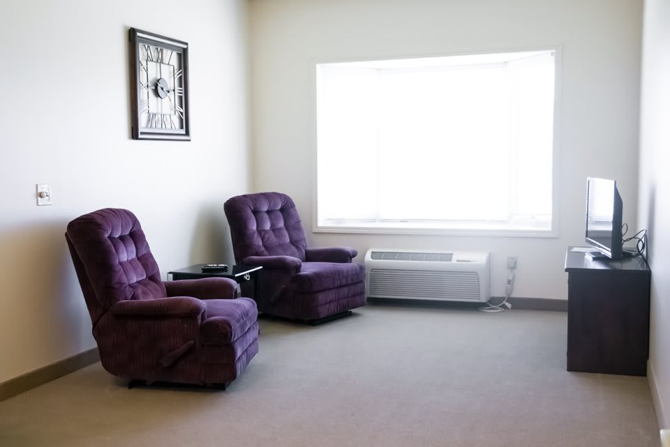 A cozy room with two purple chairs and a large window.
