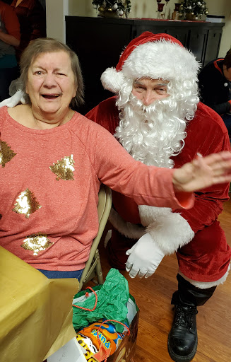 A joyful moment captured during a holiday celebration, featuring a smiling woman and Santa Claus.