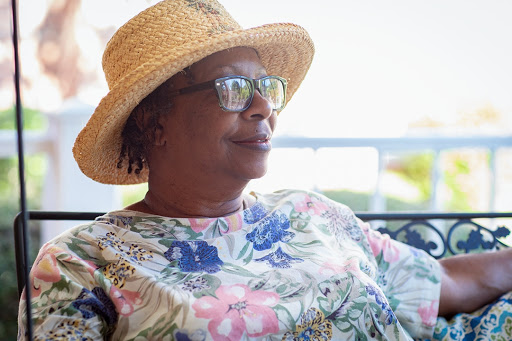 A woman enjoying a sunny day outdoors, wearing a floral shirt and a straw hat.