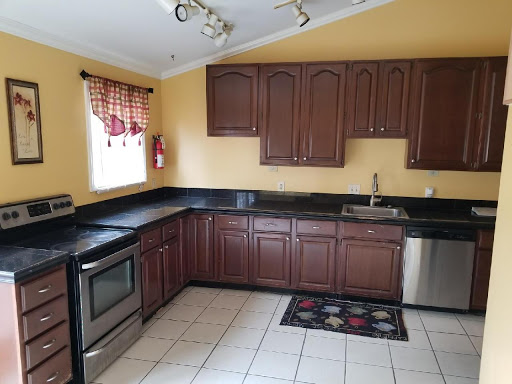 A well-lit kitchen featuring dark wood cabinets, stainless steel appliances, and a tiled floor.