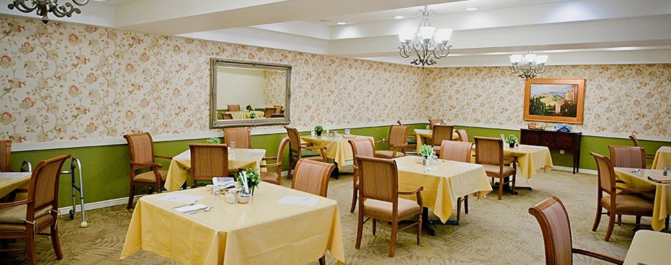 Elegant dining room with neatly arranged tables and chairs, decorated with a chandelier and wall mirror.