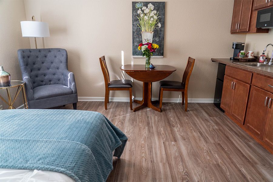 A cozy room with a bed, a small table and chairs, and a decorative painting on the wall.