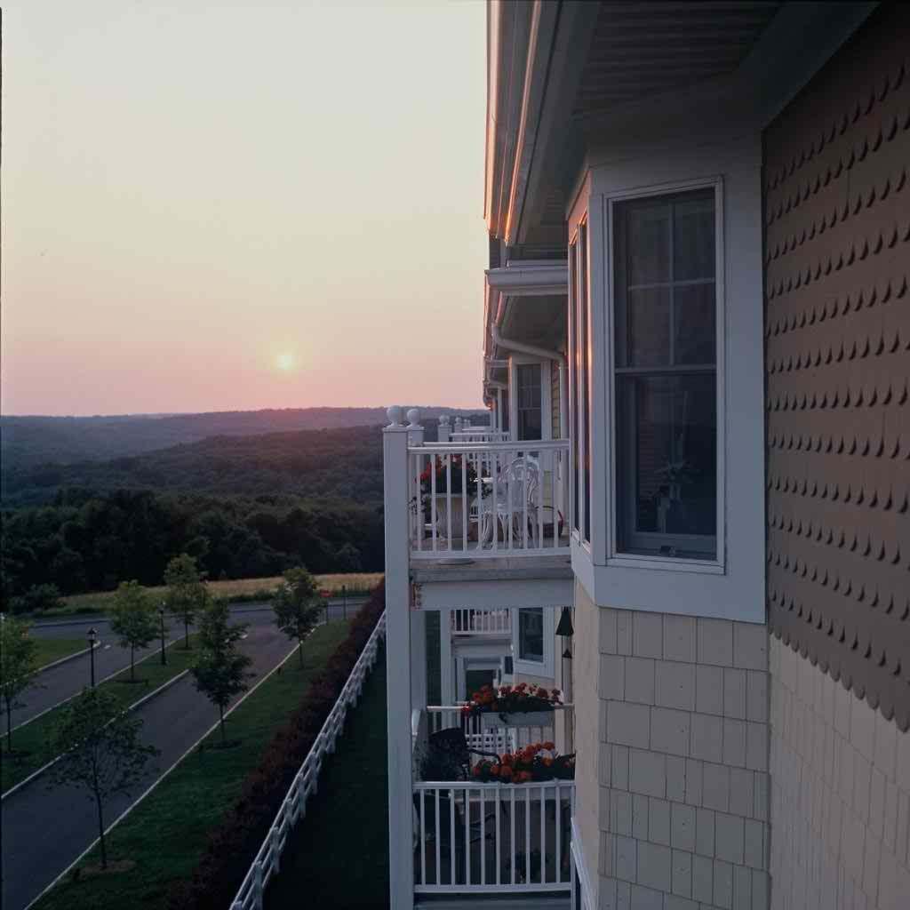 A serene sunrise view from an apartment balcony overlooking the countryside.