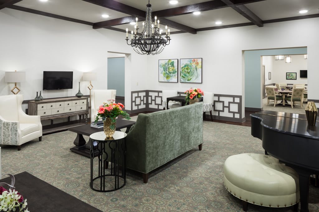 A modern living room with elegant decor, featuring a chandelier, green sofa, and stylish coffee tables.